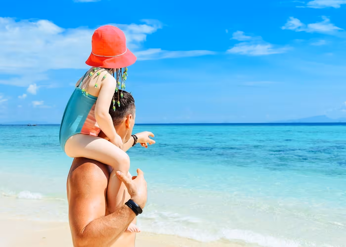 Father carrying child on shoulders enjoying pristine white sand beach with crystal clear turquoise waters during Phi Phi Islands trip