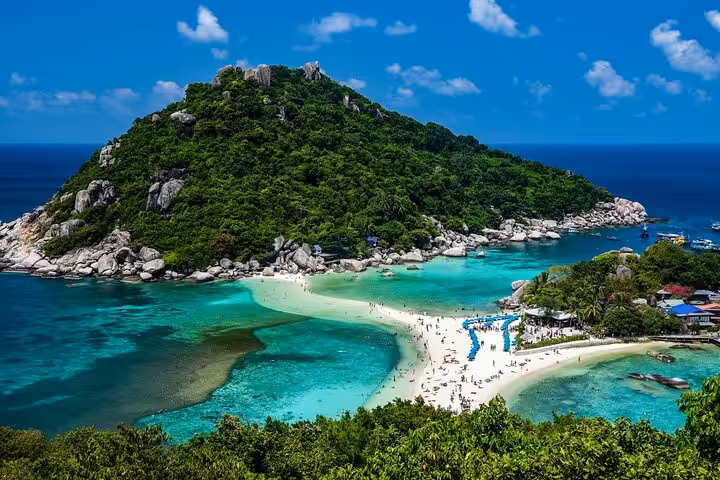 Woman in red bikini relaxing on pristine white sand beach with towering limestone cliffs and speedboats in background
